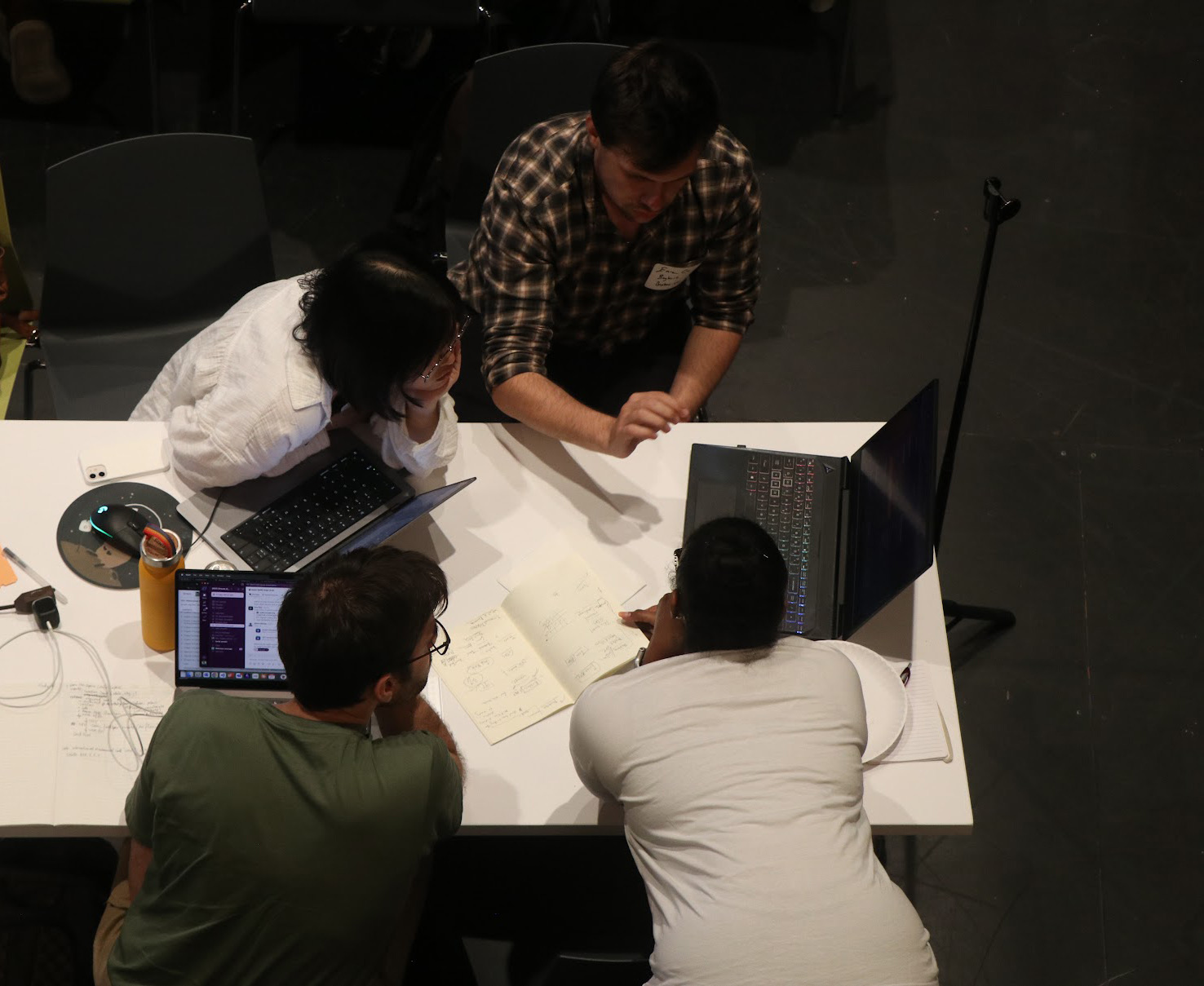Group members working together around a table with laptops and sketches